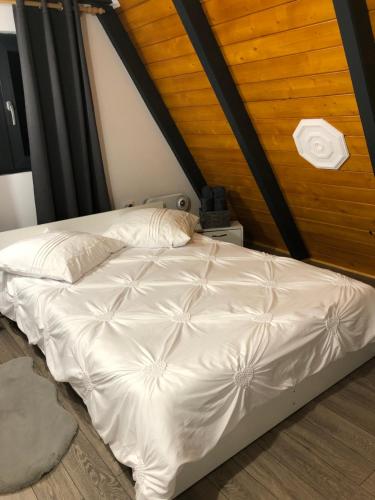 a white bed in a room with a wooden ceiling at La KOLTAU A-Frame in Mărişel