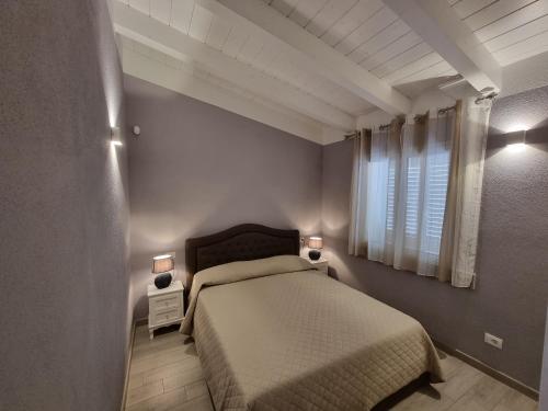Appartamento Spargi في ايزولا روسا: غرفة نوم مع سرير مع مواقف ليلتين ومصباحين