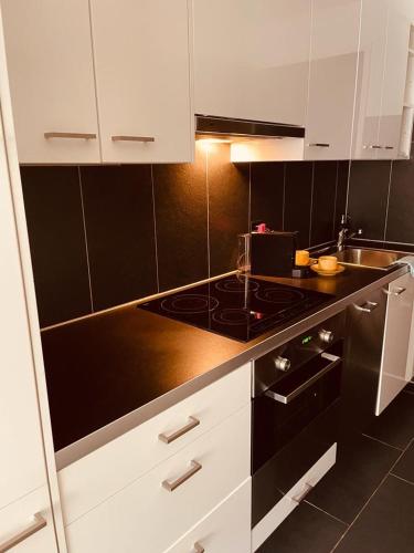 a kitchen with white cabinets and a black counter top at Haus Vitalis in Zermatt
