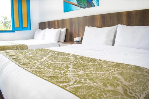 two beds in a hotel room with white sheets at Hotel Hacienda Santa Clara in Santa Rosa de Cabal