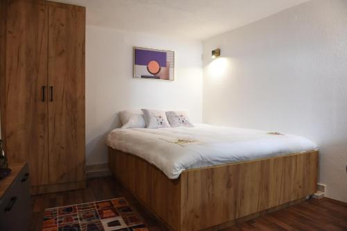 ein kleines Schlafzimmer mit einem Bett und einem Holzschrank in der Unterkunft NeWave Apartment in Strumica