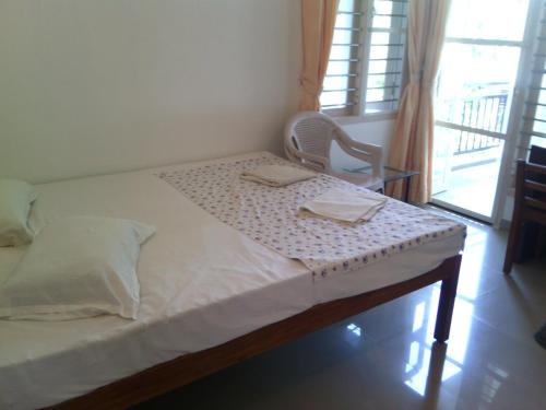 a bedroom with a bed with a chair and a window at Nathans Holiday Home in Cochin