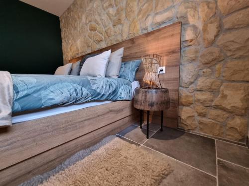 a bedroom with a bed and a stone wall at Apartments Suha Punta - Villa Babalonija in Kampor