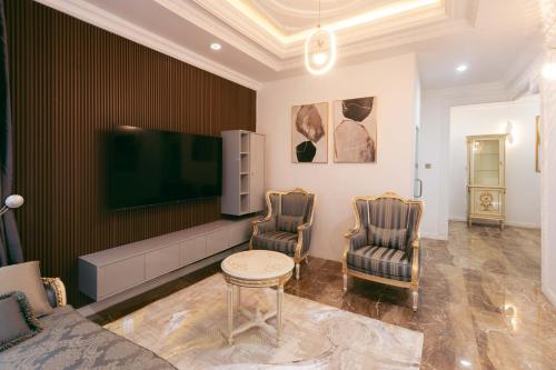a living room with a couch and two chairs and a tv at Phoenix Luxury Apartments in Abuja