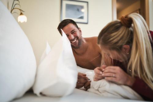 a man and a woman laying in bed at Hotel Die Arlbergerin - Design & Tiroler Gemütlichkeit in Sankt Anton am Arlberg