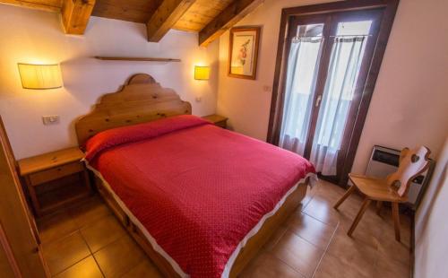 een slaapkamer met een bed met een rode deken bij Residence Borgo Al Sole in Sappada