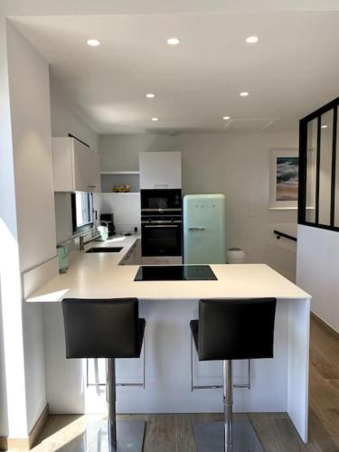 - une cuisine avec un comptoir et 2 chaises dans l'établissement La Cabane des Surfeurs, à Quiberon