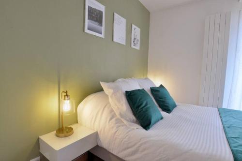 1 dormitorio con cama blanca y almohadas azules en L'Olivier Disneyland JO Paris 2024 avec Parking, en Bailly-Romainvilliers