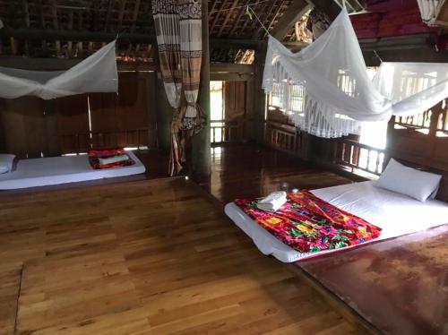 two beds in a room with wooden floors and white drapes at VuLinh Family -Homestay in Yên Bình