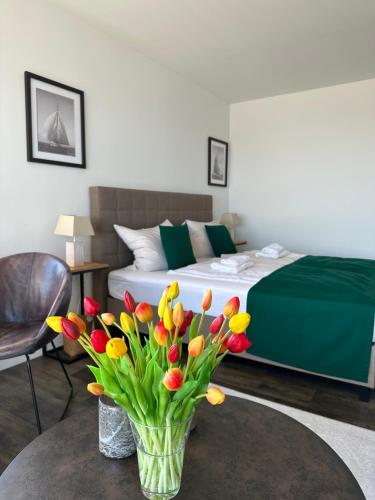 un jarrón de tulipanes sobre una mesa en un dormitorio en Weitblick - mit Strandkorb, mehr Meer geht nicht, en Glücksburg