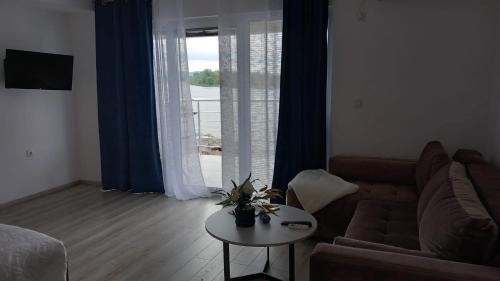 sala de estar con sofá, mesa y ventana en Lago d'argento sobe en Veliko Gradište