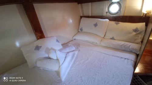 een klein bed in een kleine kamer met witte lakens en kussens bij Veliero in Legno in Bisceglie