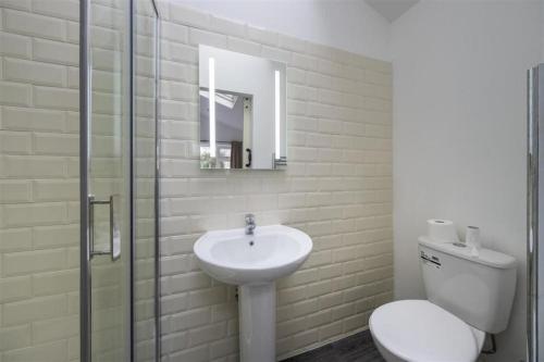 a bathroom with a sink and a toilet and a mirror at 4 Bed in the heart of Hartford in Hartford