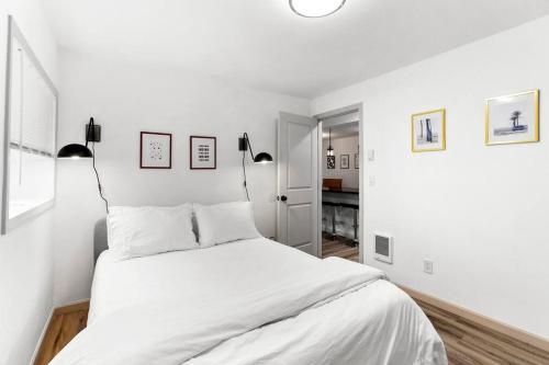 a white bedroom with a bed and two lamps at Hillside in Seattle - updated and well appointed. in Seattle