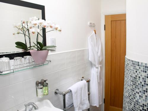 a bathroom with a sink and a vase of flowers at Pond View Cottage in Brantingham