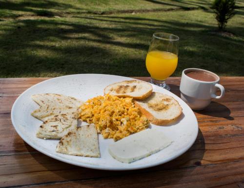 a plate of food with bread and eggs and a glass of orange juice at Hotel Hacienda Santa Clara in Santa Rosa de Cabal