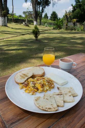 a plate of breakfast food and a glass of orange juice at Hotel Hacienda Santa Clara in Santa Rosa de Cabal