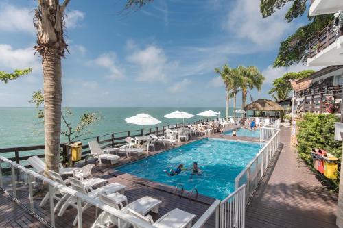 a pool with chairs and the ocean in the background at Bombinhas Tourist Apart in Bombinhas