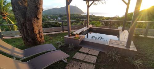 a swimming pool with a bench and a tree at Hotel - Résidence Habitation Grande Anse in Deshaies