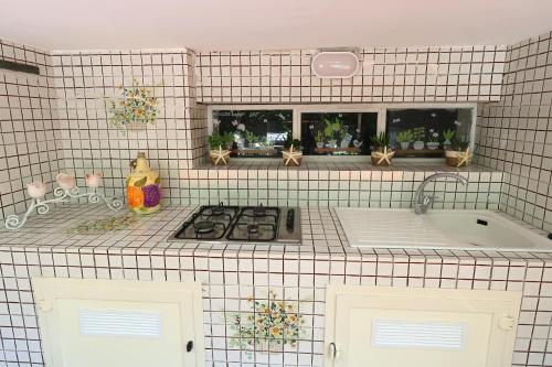 - une cuisine carrelée de blanc avec une cuisinière et une baignoire dans l'établissement Garden House Giulia, à Sorrente