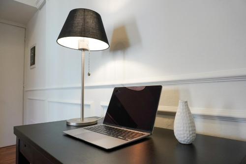 un computer portatile seduto su una scrivania accanto a una lampada di L'Alberghetto a Trinità