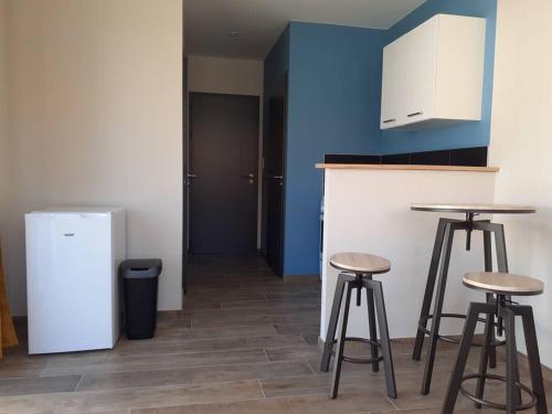 a kitchen with two bar stools and a refrigerator at chez Virginie et Jacky in Les Épesses