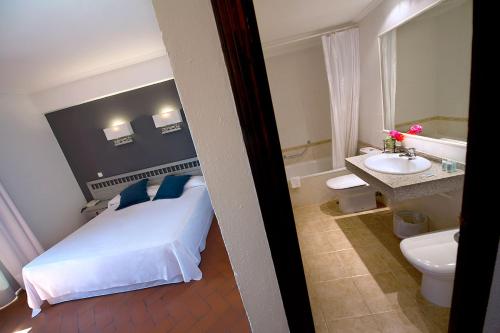 トロにあるHospedium Hotel Juan IIのベッドルーム1室(ベッド1台付)、バスルーム(シンク付)