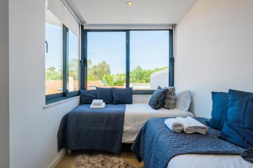 two beds in a room with large windows at Bela Vista in Cascais