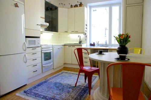 a white kitchen with a table and chairs and a table and a tableablish at Kaunis ydinkeskustan huoneisto in Tampere
