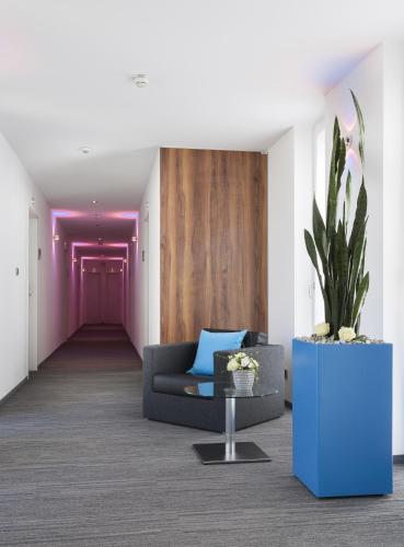 a living room with a couch and a potted plant at Best Western Hotel am Europaplatz in Königsbrunn