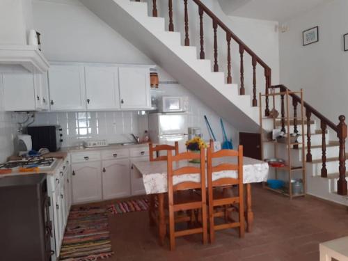 a kitchen with a table and chairs and a staircase at Casa da Açoteia, Fuseta in Fuzeta