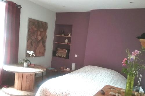 a bedroom with purple walls and a bed and a table at Abrigermaine in Arromanches-les-Bains
