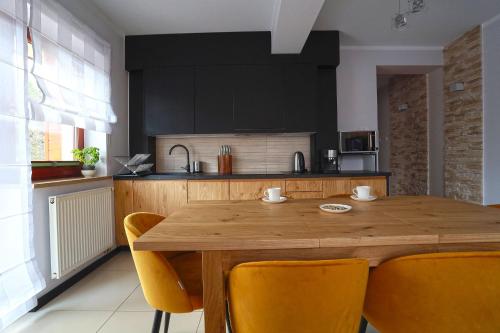 eine Küche mit einem Holztisch und gelben Stühlen in der Unterkunft Jagiellońska 34 in Zakopane
