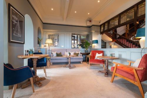 a lobby with tables and chairs and a staircase at Cliftonville Hotel in Cromer