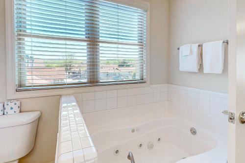 Riverside Trout Cottage في هيلين: حمام أبيض مع حوض استحمام ونافذة