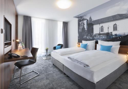 a hotel room with a large bed and a desk at Best Western Hotel am Europaplatz in Königsbrunn
