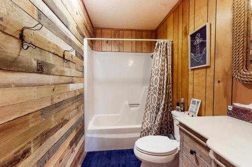 a bathroom with a toilet and a wooden wall at The Lake House in Jacksboro