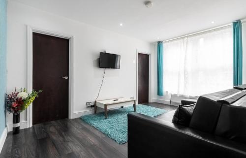 a living room with a couch and a tv on a wall at Aldgate Flats in London