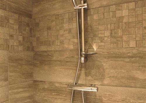 W łazience z kamienną ścianą znajduje się prysznic. w obiekcie Pheasant w mieście Saint James
