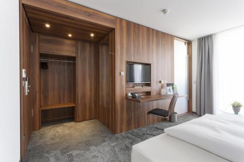 a hotel room with a bed and a desk and a television at Best Western Hotel am Europaplatz in Königsbrunn