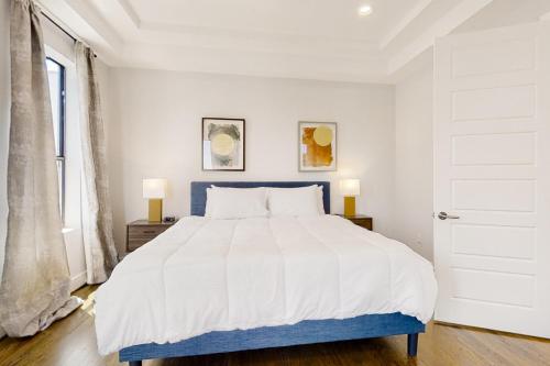 a white bedroom with a blue bed and a window at Houston's Hidden Wonder in Houston