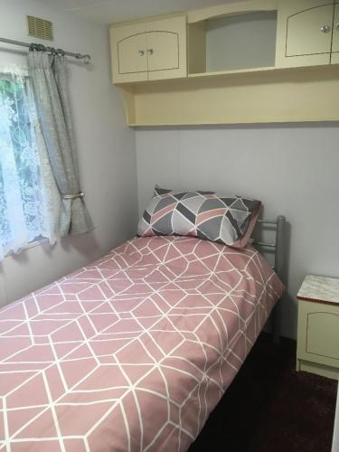 um quarto com uma cama rosa e uma janela em The Caravan at Loggans Lodge em Hayle