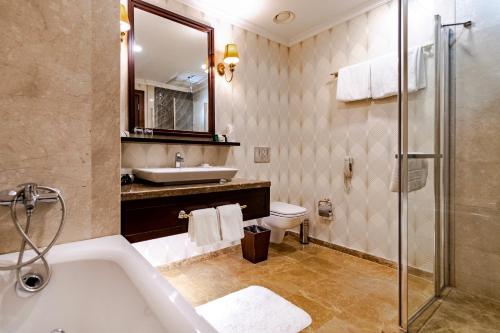 a bathroom with a tub and a sink and a toilet at Wellborn Luxury Hotel in Kocaeli