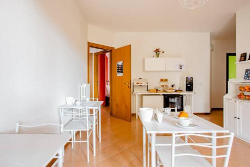 Habitación con mesas y sillas blancas y cocina. en B&B Le Palme, en Grottammare
