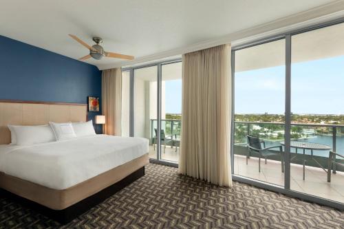 Residence Inn by Marriott Fort Lauderdale Intracoastal في فورت لاودردال: غرفة فندقية بسرير ونوافذ كبيرة