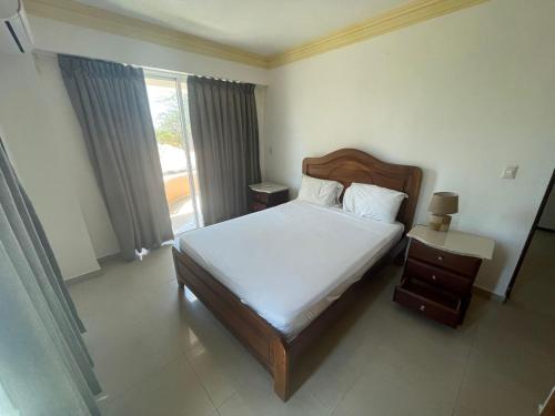a bedroom with a bed and a window at Aparta Hotel Caribe Paraiso in Juan Dolio