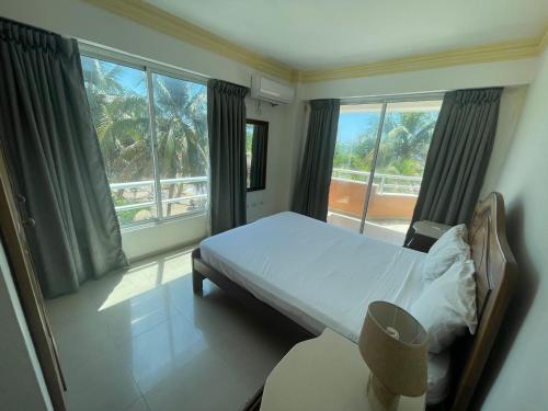 1 dormitorio con cama y ventana grande en Aparta Hotel Caribe Paraiso, en Juan Dolio