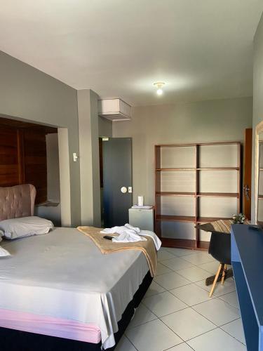 a bedroom with a bed and a desk in it at Pousada Vovo Valdir in Itapema