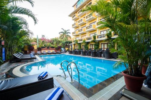 a swimming pool in front of a hotel at De Alturas Resort in Candolim