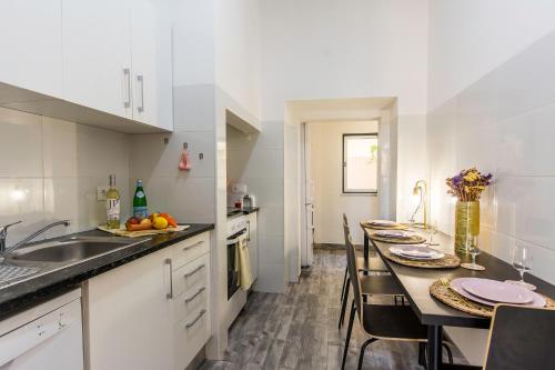 a kitchen with a sink and a table with chairs at Cozy Apartment with Patio near Carcavelos Beach in Carcavelos